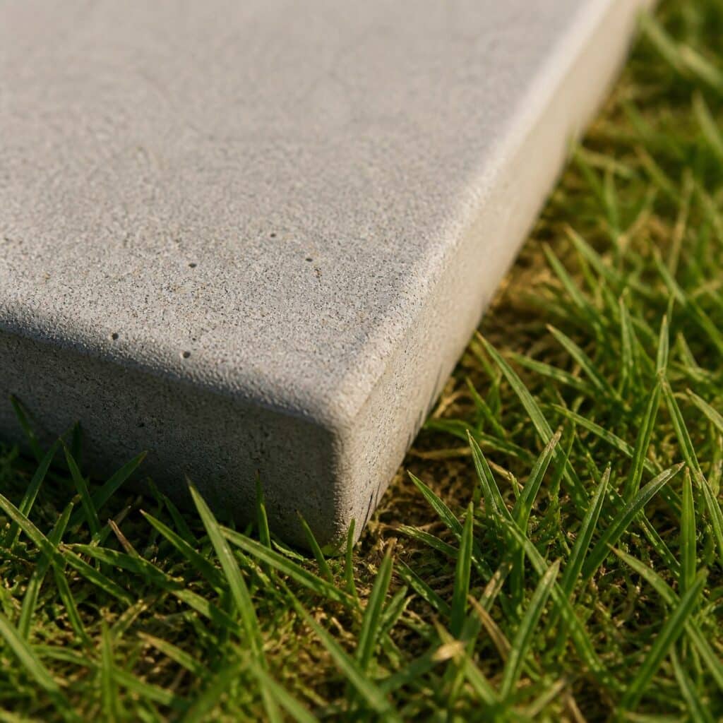 Gros plan sur le bord adouci d'une dalle béton au contact de l'herbe