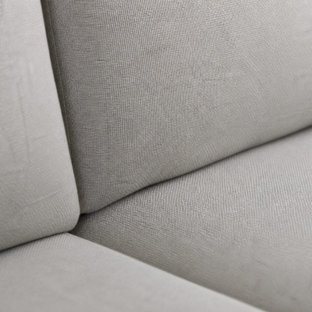 Gros plan sur le tissu rentré dans la fente entre assise et dossier au ras de la couture