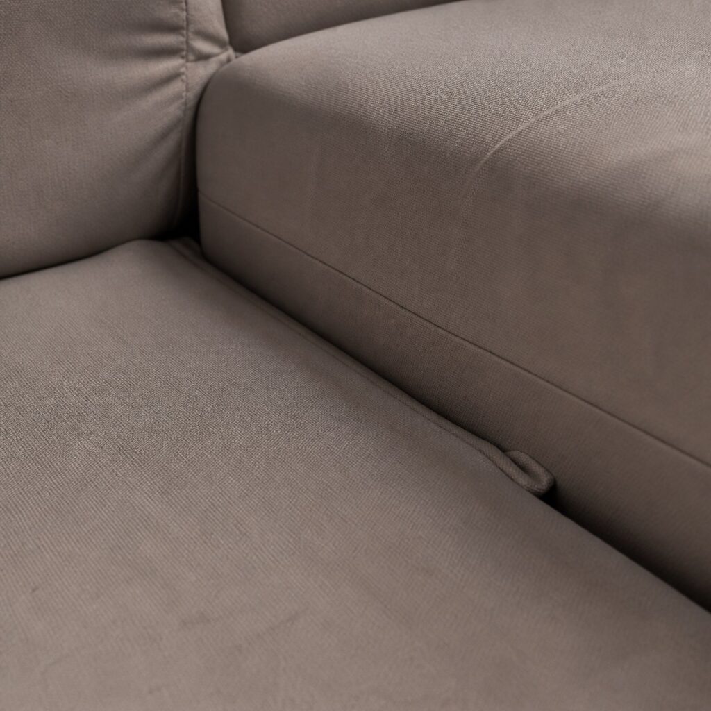 Gros plan sur le bord libre de la méridienne glissé sous l'assise et sur le raccord de tissu
