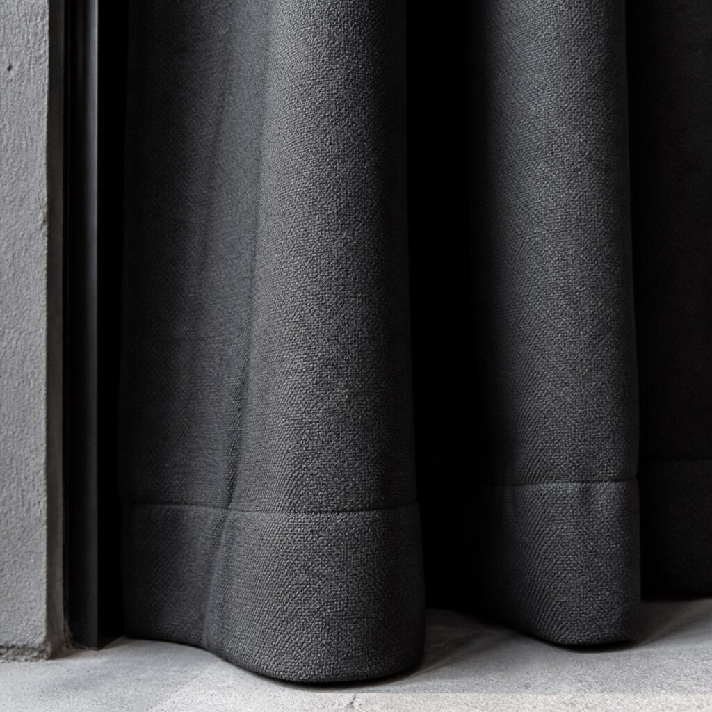 Gros plan sur l'épaisseur du textile et l'ourlet lourd d'un rideau anthracite