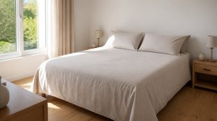 Lit deux places recouvert d'une housse de couette en coton clair bien ajustée, dans une chambre lumineuse au parquet en chêne