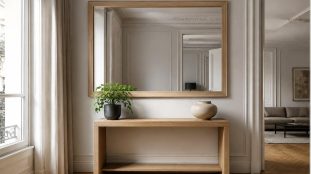 Miroir mural rectangulaire à cadre en bois clair accroché au-dessus d'une console en chêne dans une entrée lumineuse